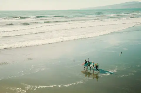A small group walking through shallow water, from above