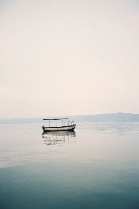 Small open boat with a sunshade on calm, hazy water