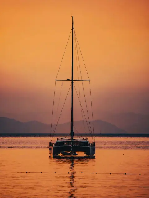 Catamaran in silhouette on an amber sea
