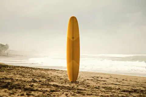 Yellow surfboard standing upright in the sand